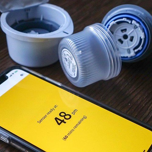 Sensore glicemico a forma di moneta applicato sull'avambraccio con display luminoso a LED