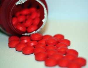 Compresse rosse fuoriescono da un flacone di medicinali