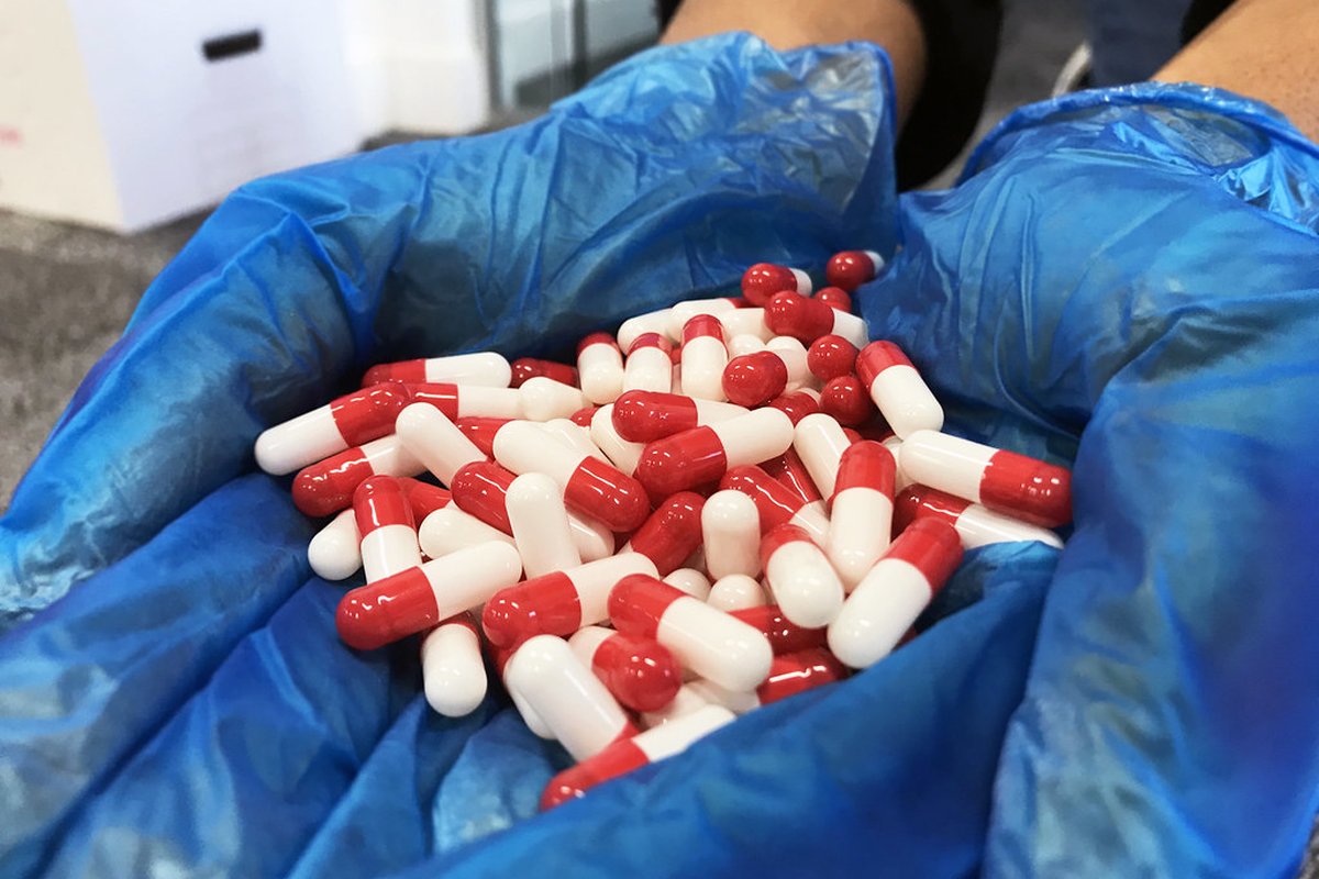 Mani con guanti tengono compresse bianche, tema farmaci