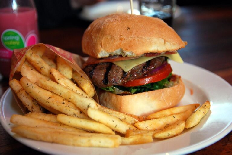 Hamburger con patatine fritte su un piatto, esempio di cibo ad alta densita calorica