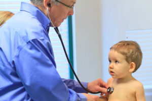 Medico con stetoscopio visita un bambino piccolo durante un controllo pediatrico