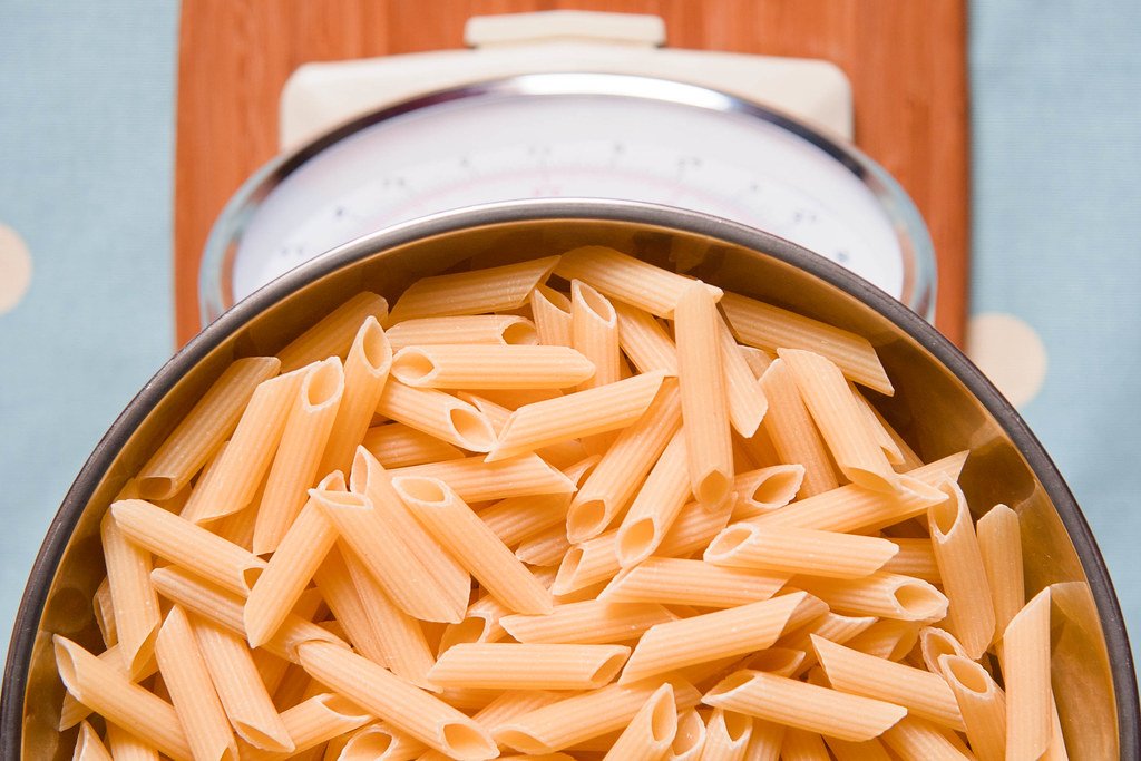 Pasta cruda su una bilancia da cucina, simbolo di dieta e controllo del peso